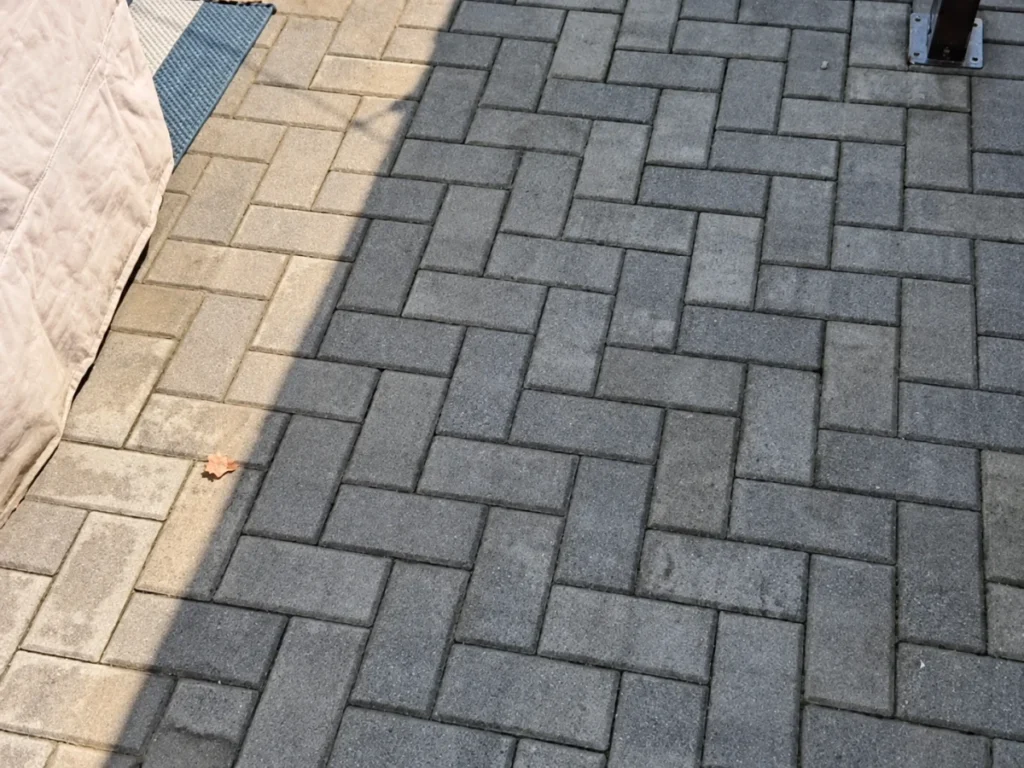 Paver stone walkway and patio beside a landscaped residential property