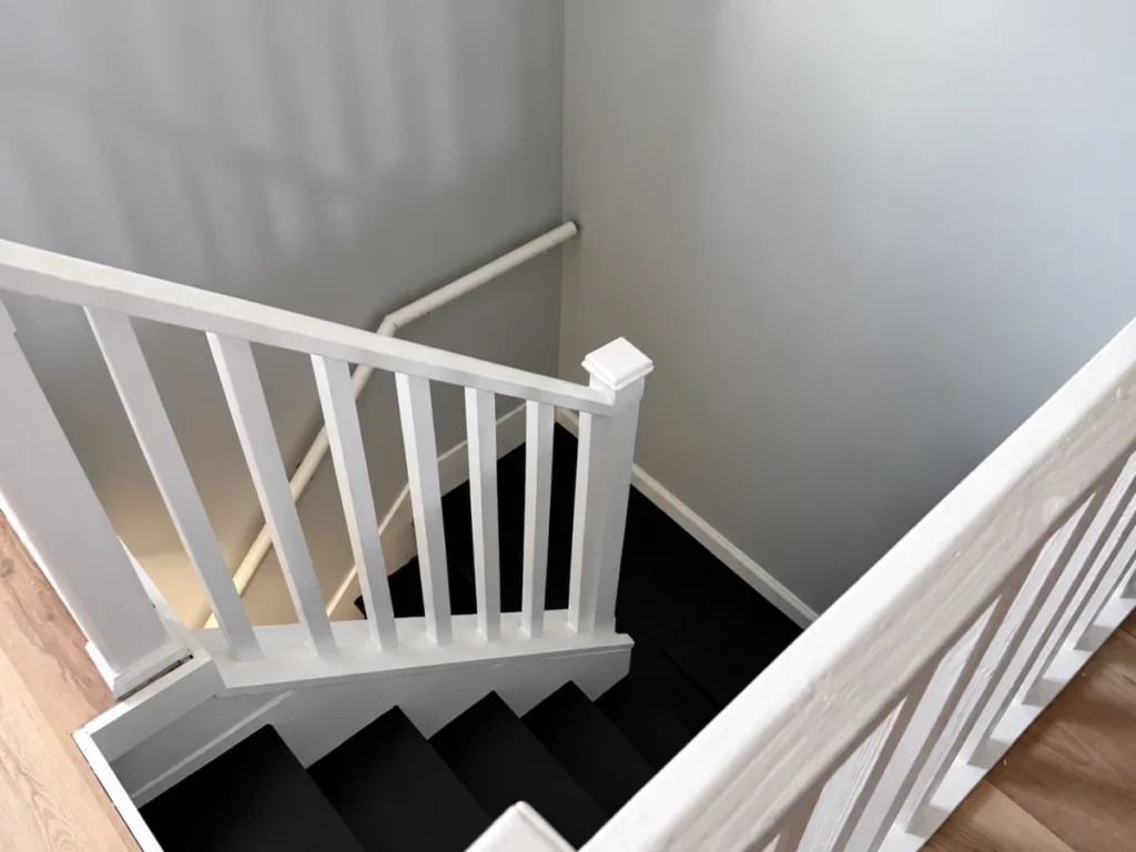 Finished interior staircase with updated flooring and railing